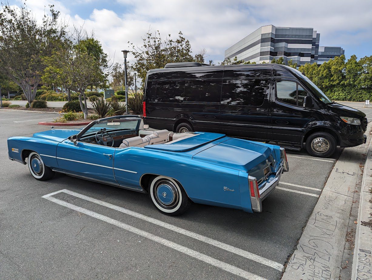 Crystal Blue & Sprinter-b930972 (1) A blue vintage convertible car parked beside a modern black van.